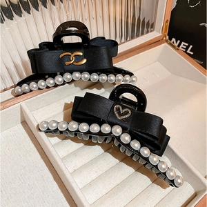 Pinces à cheveux en soie noire avec logo doré et perles blanches dans un écrin cadeau