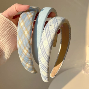 Gros plan de trois serre-têtes épais en éponge bleu clair et à carreaux tenus à la main