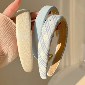 Détail de trois serre-têtes en beige plissé, bleu clair et motif à carreaux bleus