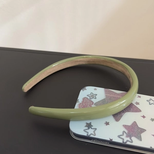 Detail of a minimalist avocado green leather headband with non-slip suede inner lining