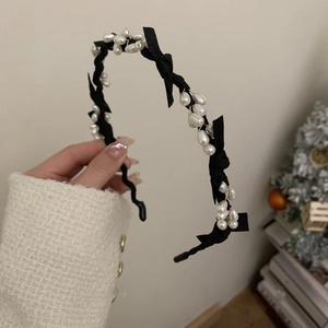 Detail of elegant black silk bow and white faux pearls on the vintage hairband