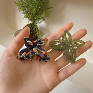 Detailed shot of acetate butterfly hair claws in marble blend and olive green
