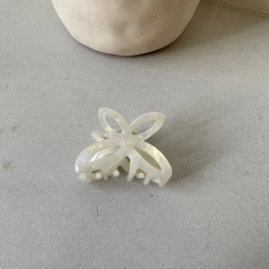 Macro shot of small ivory acetate butterfly hair claw clip with pearlescent shell texture