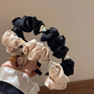 Detail of elegant black and beige pleated headbands with sparkling heart crystals