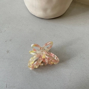 Detail of hollow butterfly hair claw with aesthetic pink and yellow marbled acetate texture