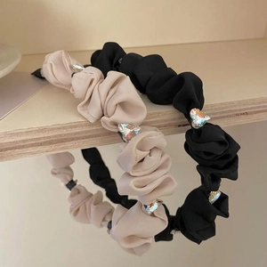 Close-up of pleated beige and black headbands with sparkling heart rhinestone details