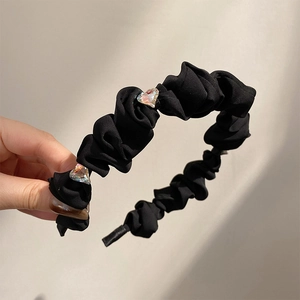 Close-up of black pleated fabric headband with two heart-shaped crystal rhinestones