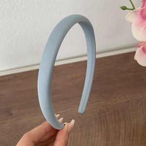 Détail d'un serre-tête en satin bleu clair rembourré tenu par la main avec éponge