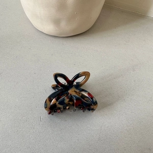 Detailed close-up of a small hollow butterfly hair claw clip with colorful leopard patterns