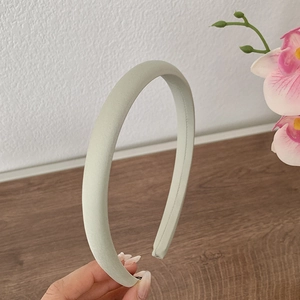 Gros plan sur un serre-tête rembourré en satin vert clair à texture mate élégante