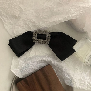 Dettaglio di un fiocco in raso nero con fibbia in strass scintillante e texture eleganti della clip