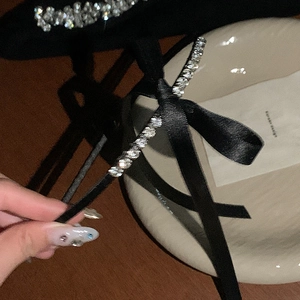 Elegant black satin headband with sparkling silver rhinestone bow on ceramic tray