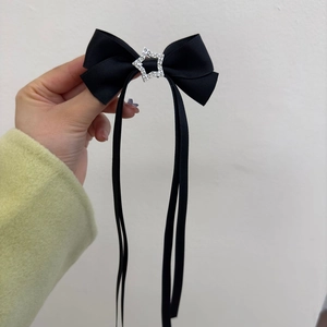 Détail d'un nœud papillon en satin noir avec strass étoile argentée et longs rubans soyeux