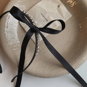 Detail of elegant black satin bow headband with sparkling rhinestones and Korean design