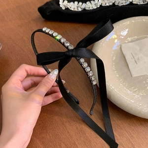 Detailed shot of a black satin bow headband with sparkling rhinestones and long ribbons