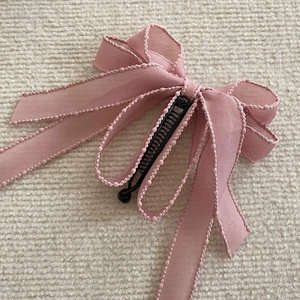 Detailed close-up of a pink bow banana hair clip with elegant beaded ribbon texture