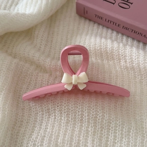 Rosa Haarklammer mit Schleife auf weißem Strickhintergrund in einer ästhetischen Szene