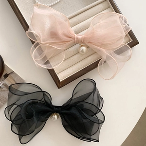 Detail of pink and black organza bow hair clips with white pearl charms in a tray