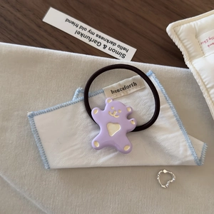 Gros plan d'un chouchou ours en résine violette avec élastique noir et détail de coeur doré