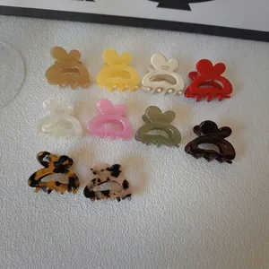 Ten butterfly-shaped hair clips in various colors arranged on white fabric