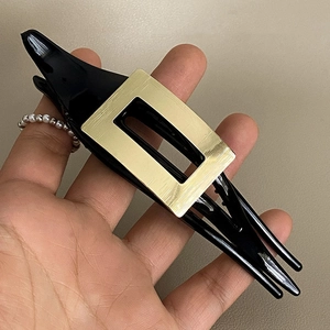 Detail einer eleganten schwarz-goldenen Haarspange mit gebürstetem Metall-Design
