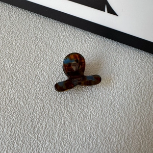 Detail view of mini acetate hair claw clip in tortoise shell with SUNSHINE text