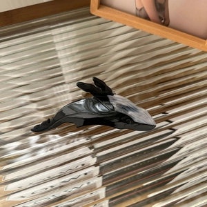 Détail de la pince à cheveux baleine en acétate noir et marbré sur surface vitrée