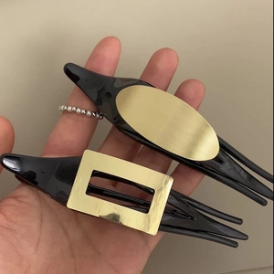 Detail der matt gebürsteten Goldmetallstruktur auf eleganten schwarzen Haarspangen