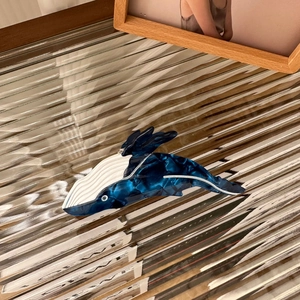 Détail d'une pince à cheveux en acétate en forme de baleine avec texture marbre bleu