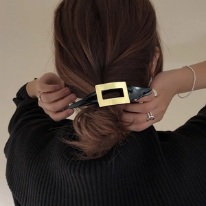 Minimalistische große schwarze Haarspange mit Goldmetall-Akzent auf elegantem Dutt