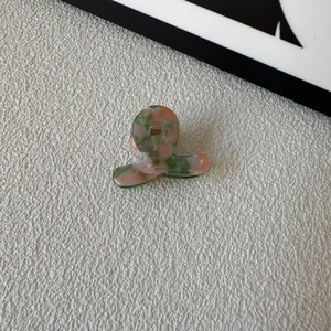 Macro detail of handmade mini acetate hair claw clip with pink and green marble texture