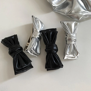Détail des barrettes nœud argentées et noires avec texture métallique et pince crocodile