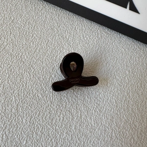 Detail of a dark tortoiseshell cellulose acetate mini hair claw clip with handmade engraving