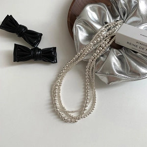Collier à plusieurs rangs de perles argentées et pinces à cheveux avec nœud en cuir noir