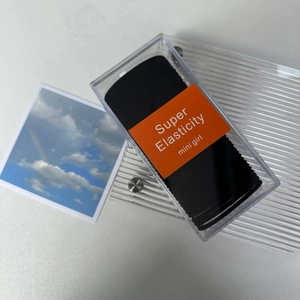 Macro shot of durable black elastic hair ties set in a transparent box with orange label