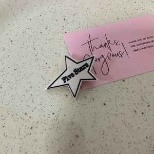 Détail macro d'une pince à cheveux étoile en acrylique avec texte Five Stars sur marbre