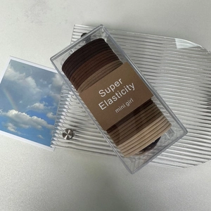 Detail of high elasticity hair ties in earthy tones inside a clear storage box