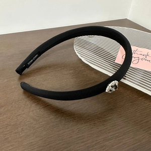 Close-up of handmade black fabric headband with sparkling crystal heart on wooden table