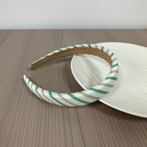 Close-up of a wide green and white striped headband on a white marble display plate