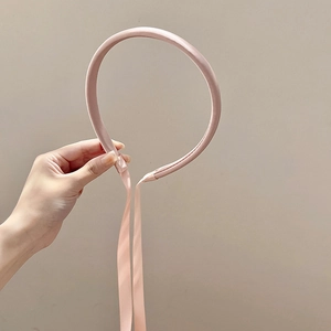 Détail d'un serre-tête fin en satin rose orné de longs rubans élégants pour femme