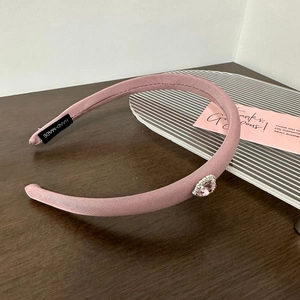 Detail of pink fabric headband featuring a central teardrop rhinestone and hand-made label