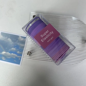 Macro detail of purple elastic hair ties in a clear rectangle storage box for girls