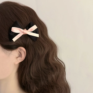 Gros plan d'une pince à cheveux à double nœud en ruban de soie sur cheveux bouclés