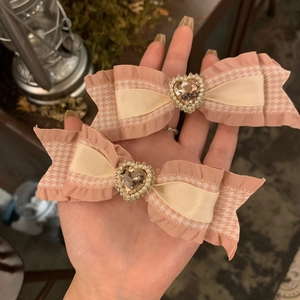 Détail de barrettes nœuds roses avec pierre en forme de cœur et perles élégantes