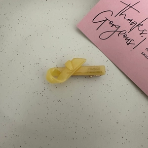 Detail showing translucent yellow acetate bow hair clip with France Handmade engraving