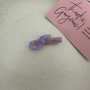 Detail view of a lavender purple resin bow hair clip with a golden metal duckbill clip