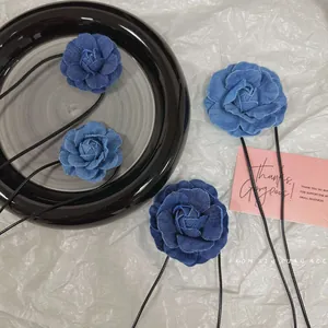 Détail de quatre colliers choker camélia en denim bleu avec rubans noirs sur plateau