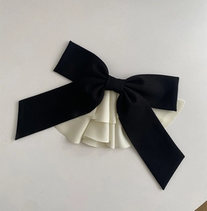 Detail of oversized black and cream satin bow hair clip with layered pleated edges