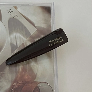 Detail shot of a dark brown tortoiseshell acetate hair clip with French lettering