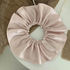 Elegant oversized light pink satin hair scrunchie with small pearl details on white surface